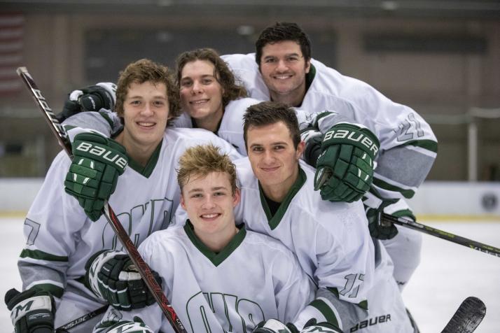 Hockey players pose together on the ice