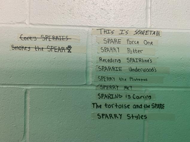 Phrases are written on tape and taped to the wall