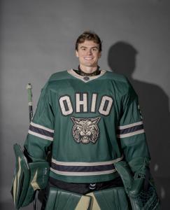 Garrett Alderman posing in his jersey, goalie mitts, and guards