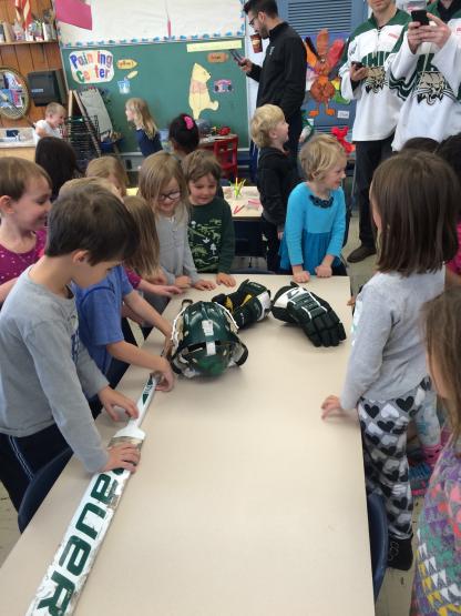 Elementary children look at OHIO Hockey equipment in their classroom
